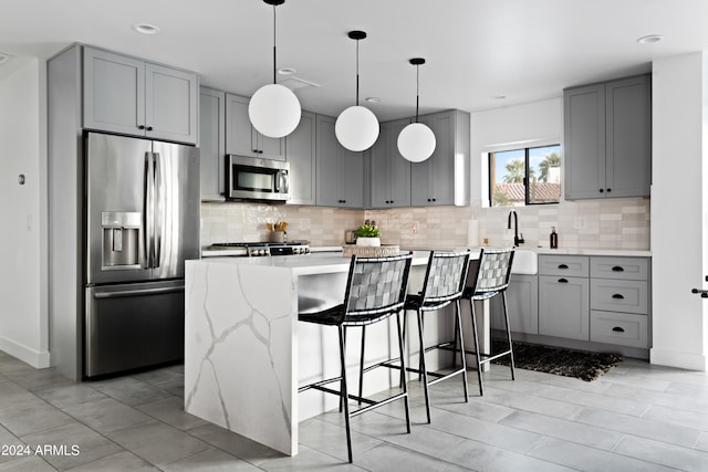 kitchen with a breakfast bar area, stainless steel appliances, hanging light fixtures, and decorative backsplash