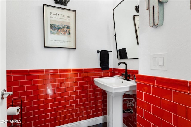 bathroom featuring sink and tile walls