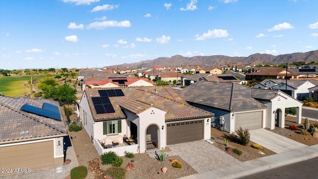 view of front facade featuring a mountain view, a garage, and solar panels