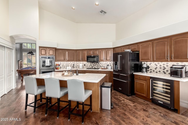 2058 E Marlene Dr, Gilbert, AZ 85296 - kitchen with wine cooler, black appliances, a towering ceiling, tasteful backsplash, and a center island with sink