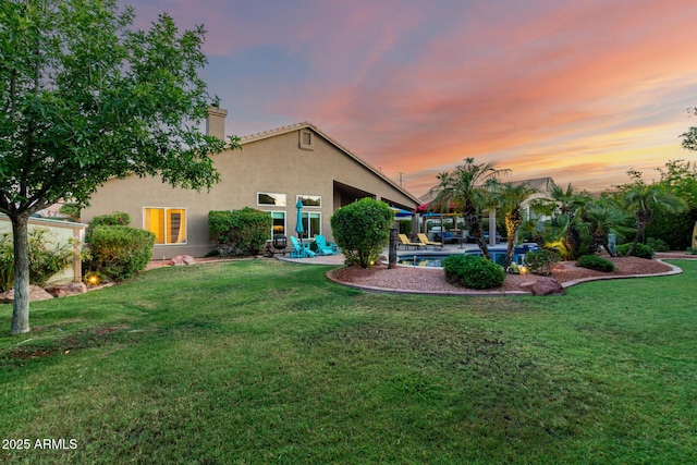 2058 E Marlene Dr, Gilbert, AZ 85296 - back of property at dusk featuring stucco siding, a chimney, a patio, a lawn, and an outdoor pool