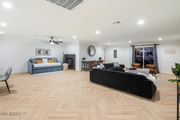 living room with ceiling fan, a fireplace, and light parquet floors