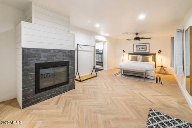 bedroom with a multi sided fireplace, ceiling fan, and light parquet flooring