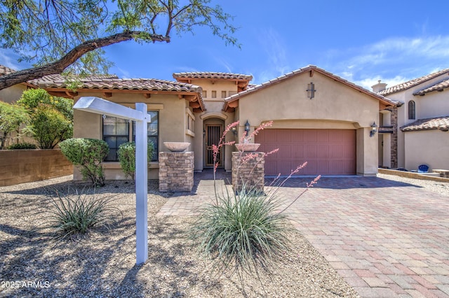 mediterranean / spanish-style house featuring decorative driveway, a garage, a tile roof, and stucco siding