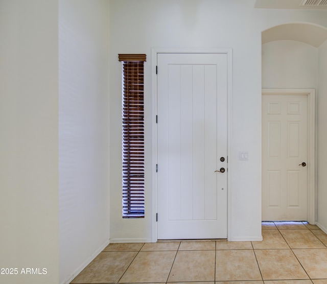 foyer entrance featuring baseboards, light tile patterned floors, and visible vents