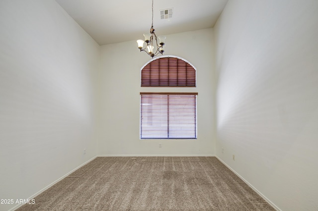 carpeted spare room with baseboards, a chandelier, and visible vents