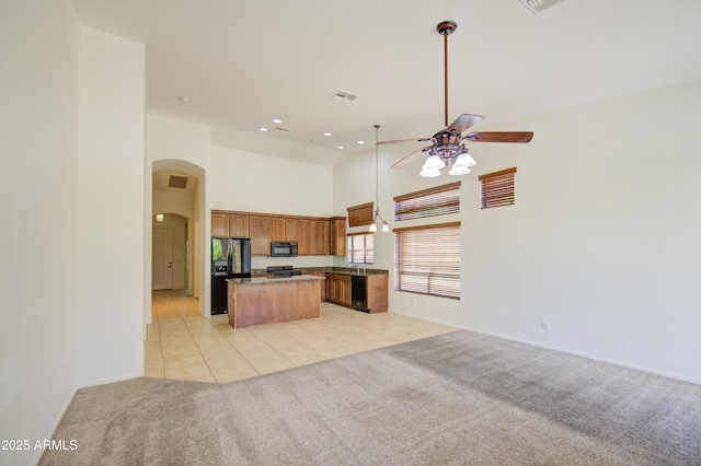kitchen featuring ceiling fan, light carpet, a center island, open floor plan, and black appliances