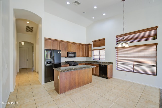 kitchen with arched walkways, high vaulted ceiling, a kitchen island, visible vents, and black appliances