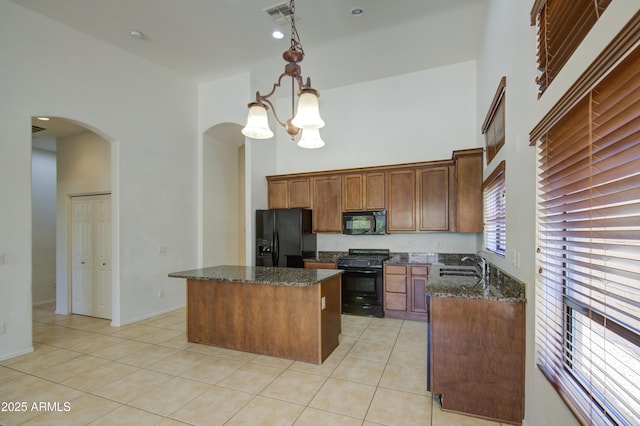 kitchen with visible vents, arched walkways, a sink, light tile patterned floors, and black appliances