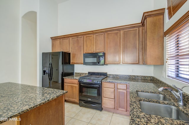 kitchen featuring a high ceiling, a sink, brown cabinetry, light tile patterned floors, and black appliances