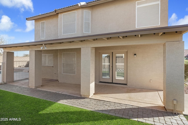 rear view of property featuring a patio area, fence, and stucco siding