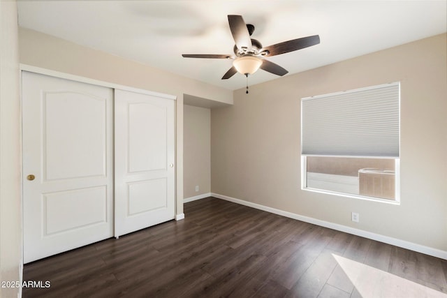 unfurnished bedroom with ceiling fan, a closet, dark wood finished floors, and baseboards