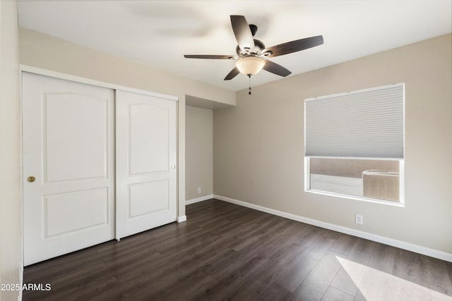 unfurnished bedroom with dark wood-style floors, a closet, a ceiling fan, and baseboards