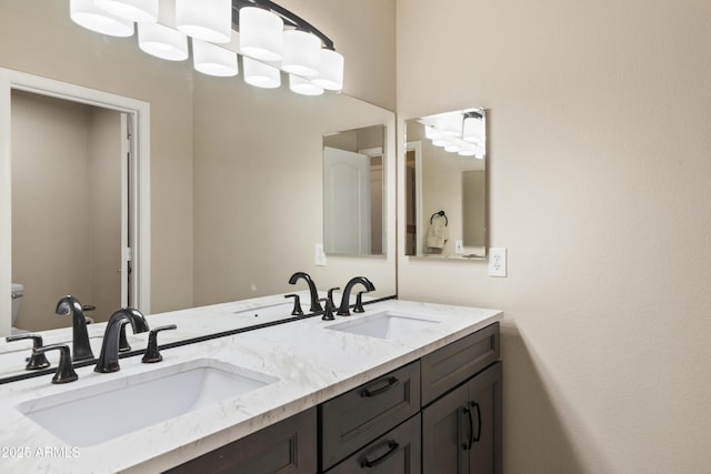 bathroom with double vanity, toilet, and a sink