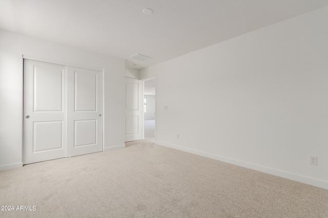 unfurnished bedroom featuring a closet and light colored carpet