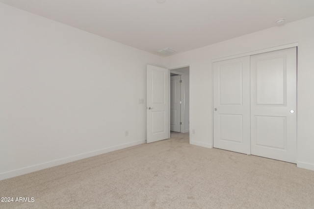 unfurnished bedroom with a closet and light colored carpet