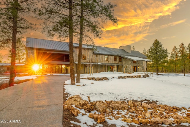 4840 E Gandalf Ln, Flagstaff, AZ 86004 - view of front of home featuring a chimney, stone siding, concrete driveway, and metal roof