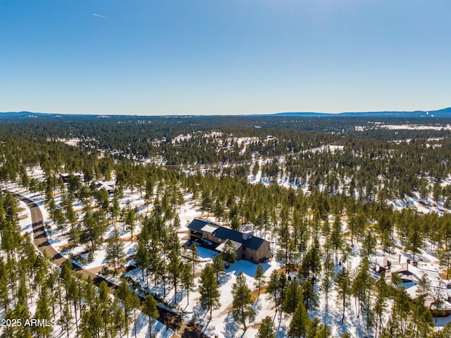 snowy aerial view with a mountain view and a forest view