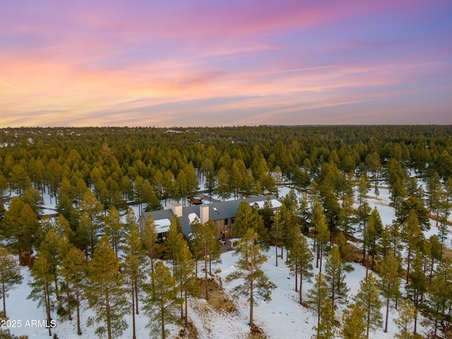 aerial view at dusk featuring a forest view