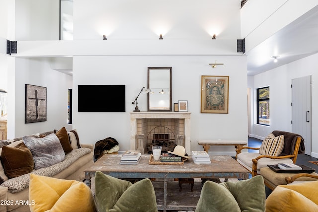 living room featuring a high ceiling, a fireplace, and baseboards