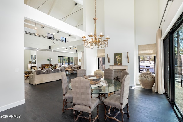 dining area with dark wood-style floors, baseboards, high vaulted ceiling, and an inviting chandelier