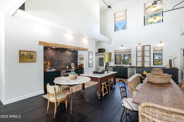 dining room with dark wood finished floors, a high ceiling, and baseboards