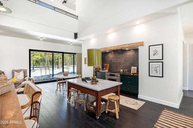 dining space with a high ceiling, dark wood-style floors, and baseboards