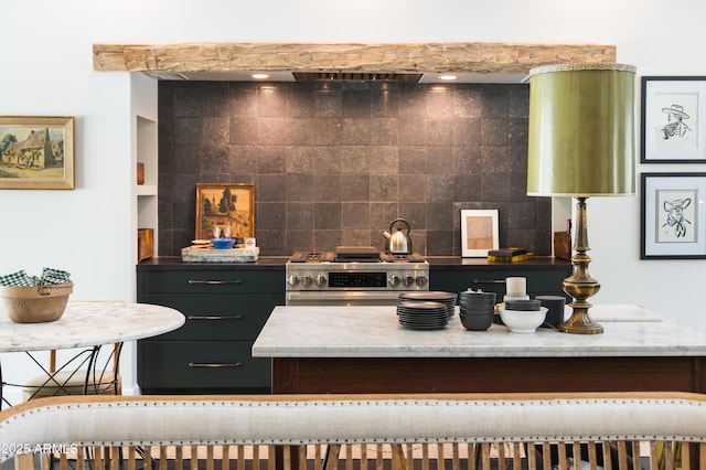 kitchen with stainless steel gas range oven, decorative backsplash, and light stone counters