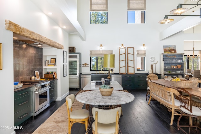 kitchen with dark wood finished floors, backsplash, appliances with stainless steel finishes, and a high ceiling