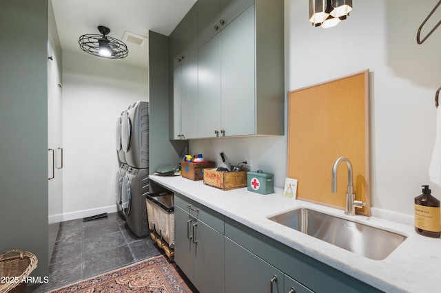 kitchen featuring a sink, stacked washer / drying machine, gray cabinets, and light countertops