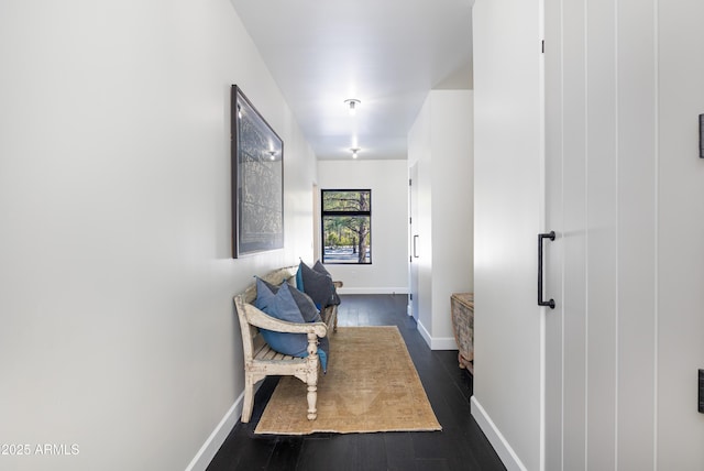 corridor featuring dark wood-type flooring and baseboards