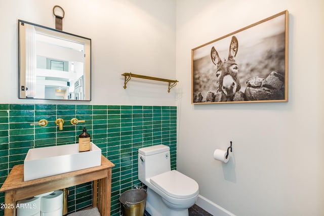 bathroom with a wainscoted wall, toilet, and tile walls