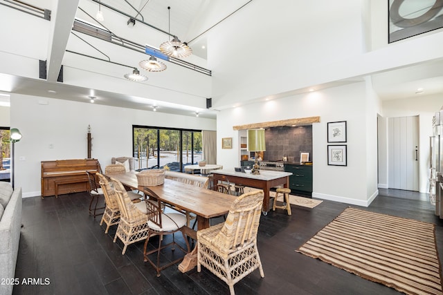 dining area featuring dark wood finished floors, recessed lighting, baseboards, and a towering ceiling