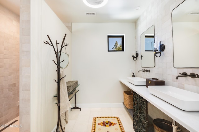 bathroom featuring decorative backsplash, dual sinks, baseboards, and visible vents