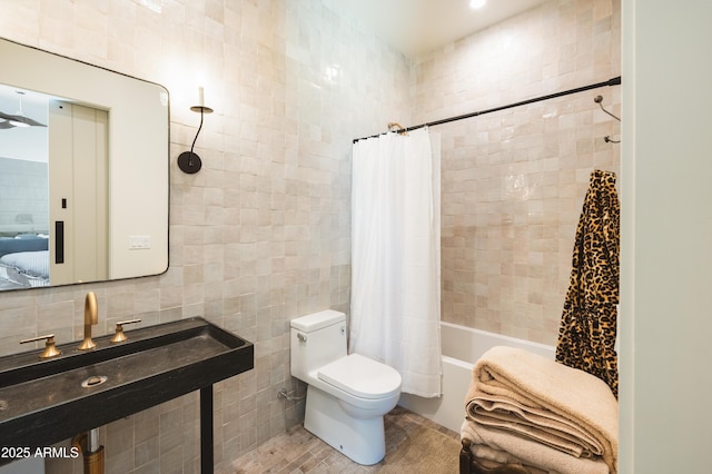 full bath with shower / bath combo with shower curtain, toilet, a sink, tasteful backsplash, and tile walls