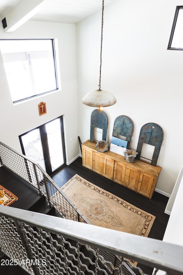 foyer entrance featuring baseboards, stairs, a towering ceiling, and dark wood-style flooring