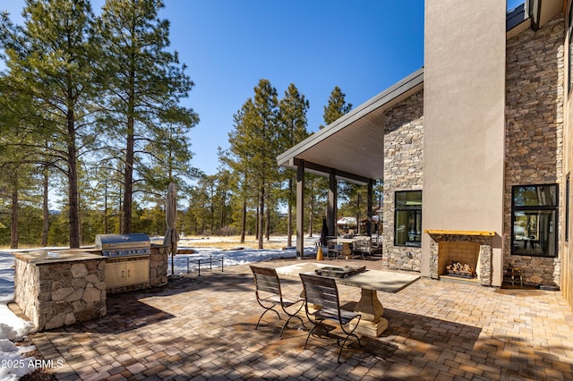 view of patio / terrace with area for grilling and an outdoor stone fireplace