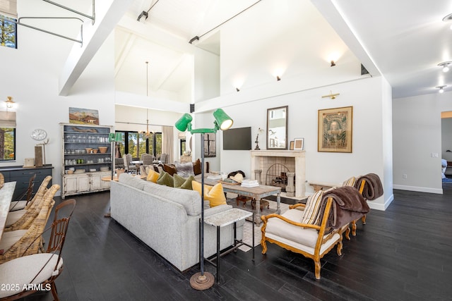 living room with high vaulted ceiling, a notable chandelier, wood finished floors, a fireplace, and baseboards