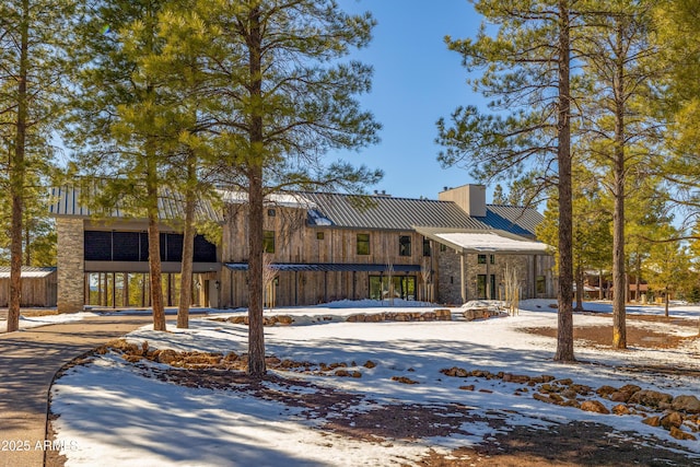 view of front facade featuring metal roof, a chimney, and a standing seam roof