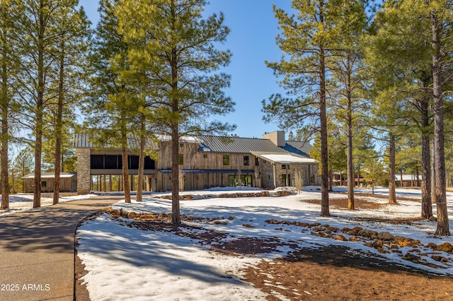 view of front of property with metal roof, stone siding, and a chimney