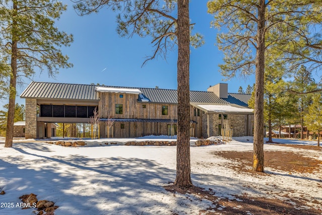 view of front facade featuring a chimney, metal roof, and a standing seam roof