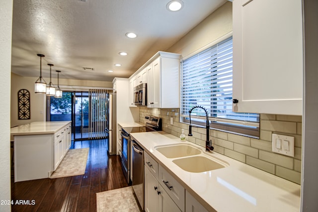 kitchen with white cabinetry, sink, dark hardwood / wood-style floors, pendant lighting, and appliances with stainless steel finishes