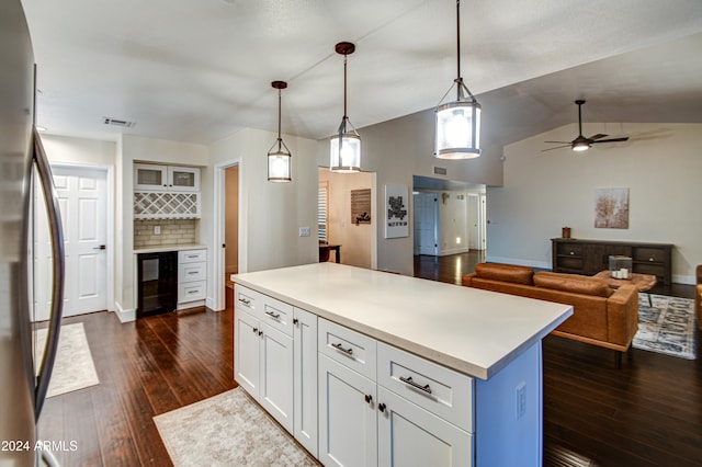 kitchen featuring stainless steel refrigerator, white cabinetry, dark wood-type flooring, pendant lighting, and a kitchen island