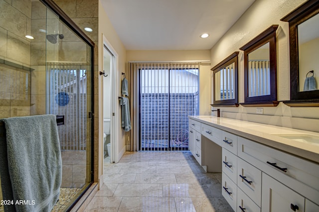 bathroom featuring a shower with door, vanity, and toilet