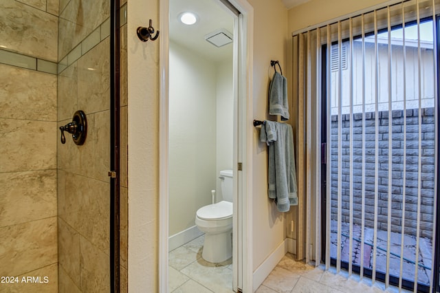 bathroom featuring a tile shower, tile patterned floors, and toilet