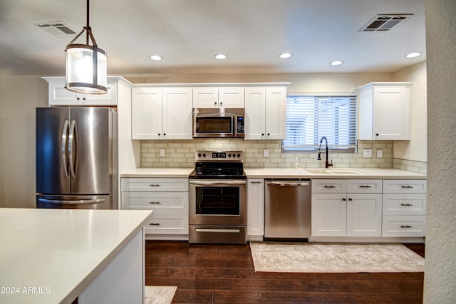 kitchen featuring dark hardwood / wood-style flooring, stainless steel appliances, sink, white cabinetry, and hanging light fixtures