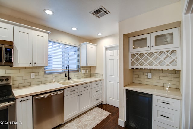 kitchen with wine cooler, dark hardwood / wood-style floors, backsplash, white cabinets, and appliances with stainless steel finishes