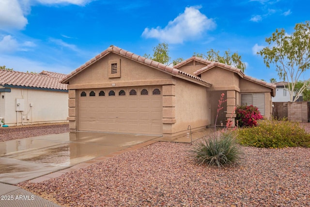 view of front of home featuring driveway, a tile roof, an attached garage, fence, and stucco siding