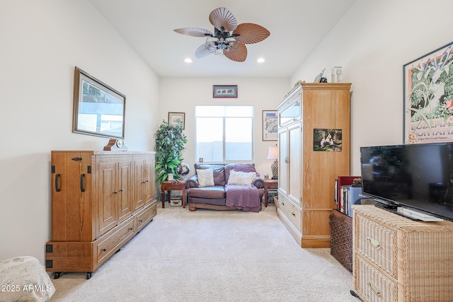 living area featuring light carpet and ceiling fan