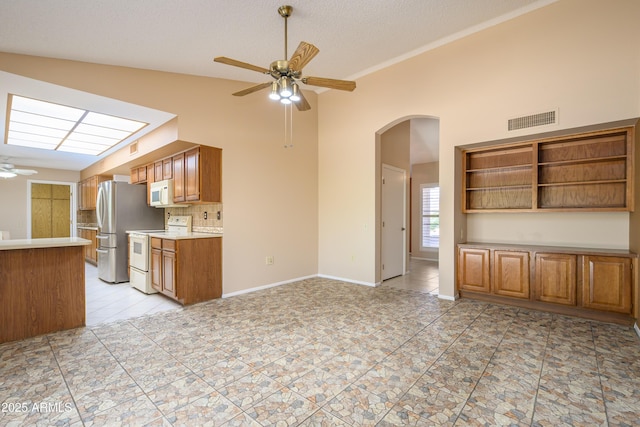 13721 W Franciscan Dr, Sun City West, AZ 85375 - kitchen featuring white appliances, ceiling fan, light tile patterned flooring, arched walkways, and high vaulted ceiling